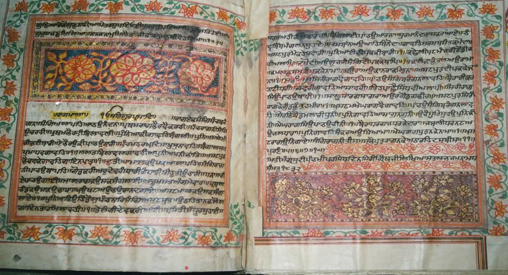 A handwritten Saroop of Sri Guru Granth Sahib Ji open at Raagmala, with painted floral borders